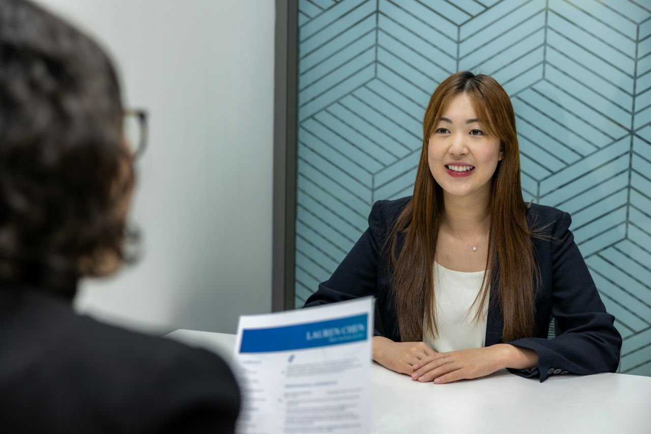Confident, Beautiful Asian Woman in suit is smiling during job interview in office environment