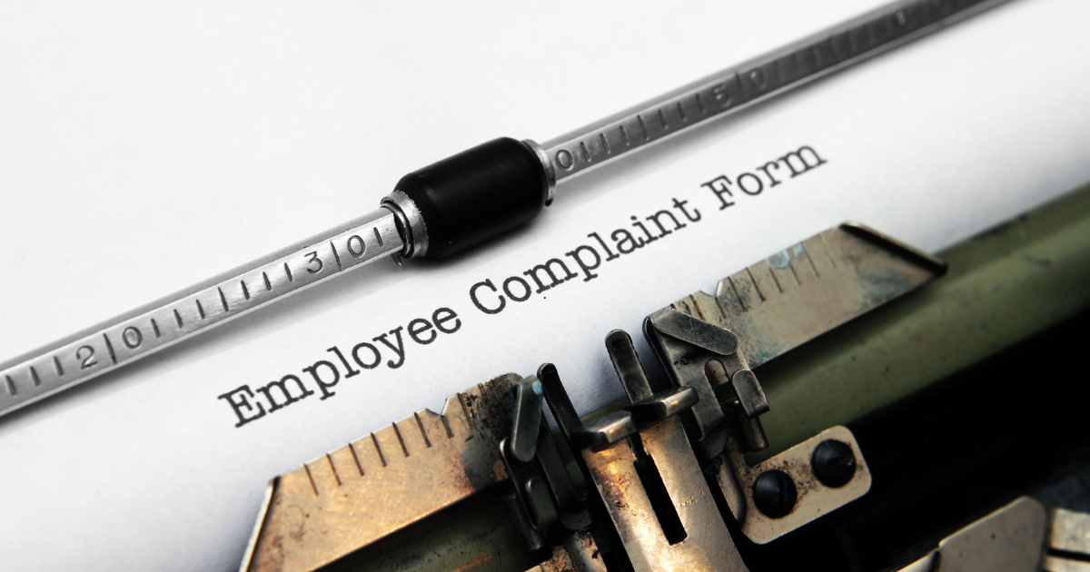 Close-up of a vintage typewriter typing a sheet that reads 'Employee Complaint Form'.